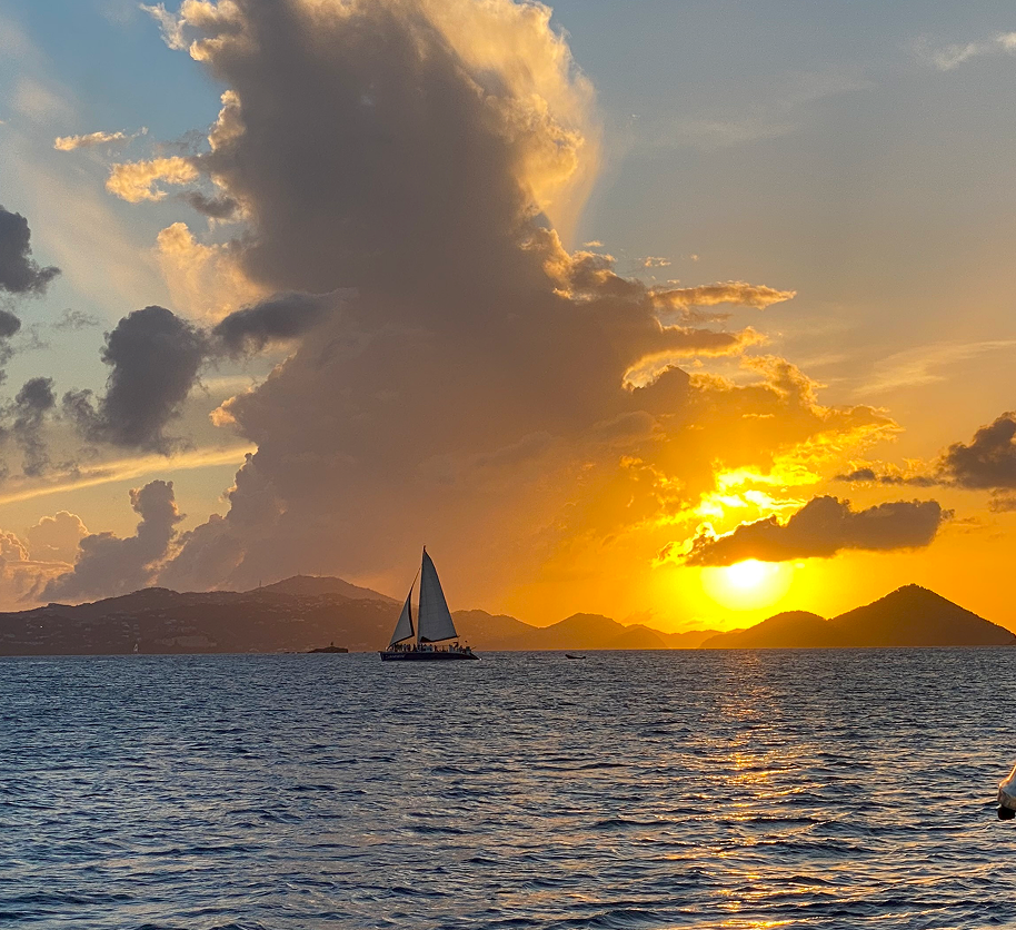 a yacht with sales in the horizon and a setting sun